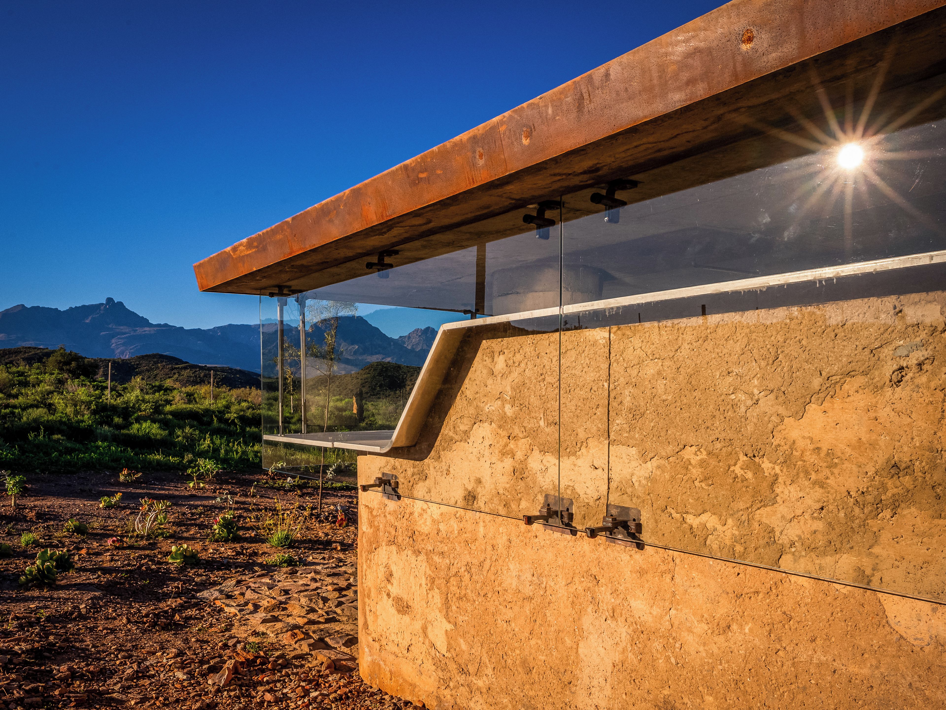 A building with a concrete exterior and a glass window, overlooking a mountainous landscape.