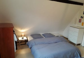 Une chambre à coucher comprenant un lit, des tables de chevet, une lampe, une armoire et une commode.