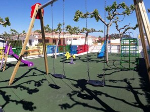 Ein Spielplatz mit Schaukeln und einer Rutsche.