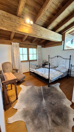 A room with a bed, a chair, a table, and a large fur rug.