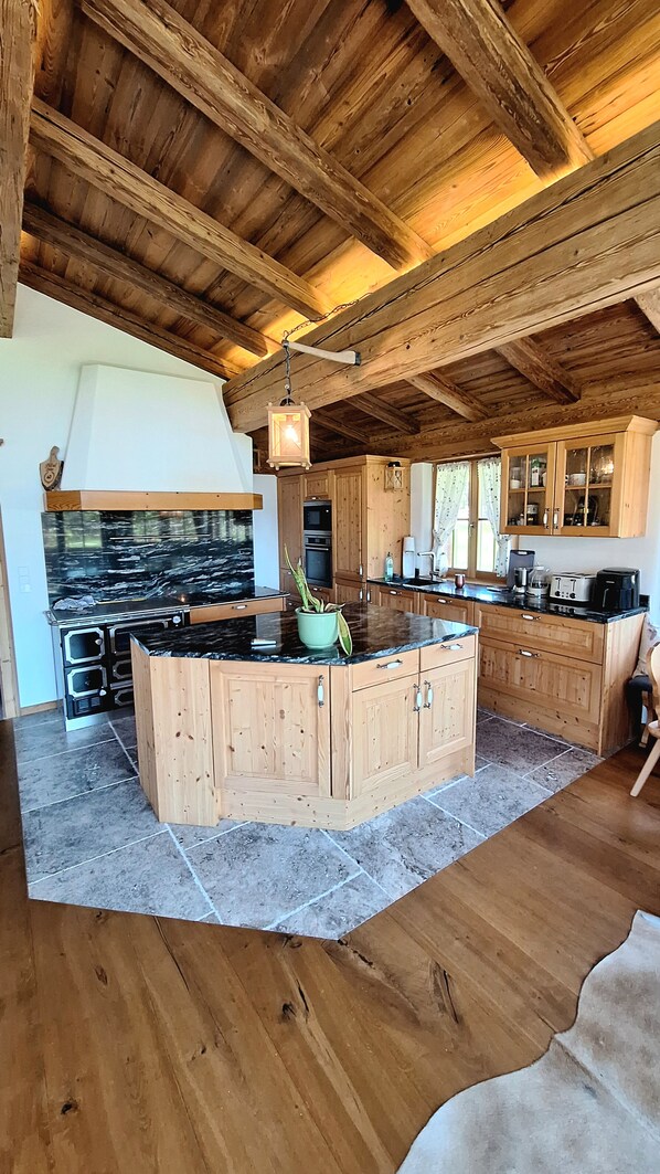A spacious kitchen with wooden cabinets, a large island, and a stone countertop.