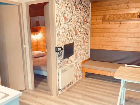 Ein gemütliches Zimmer mit einem Bett, einer Bank und einem an der Wand befestigten Fernseher.