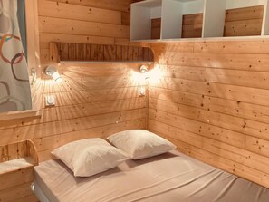 Ein Zimmer in einer Holzhütte mit einem Bett, zwei Kissen und Wandleuchten.