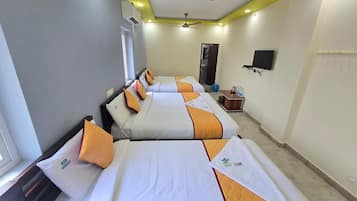 A hotel room with three beds, a ceiling fan, a flat-screen TV, and a small table with a water bottle.