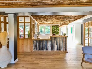 En reception med en trædisk, et stort vindue og et loft med synlige bjælker.