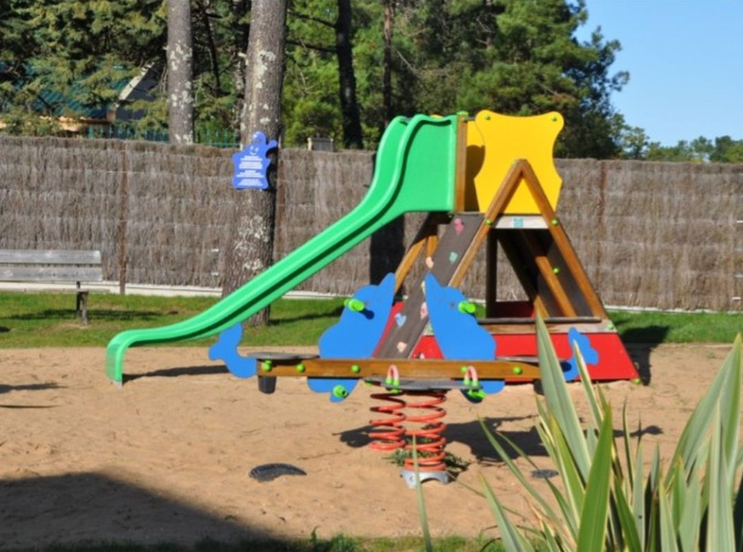 Un parque infantil con tobogán, columpios y una estructura para escalar.