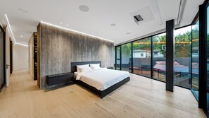 Un dormitorio moderno con una cama grande, armario empotrado y puerta corredera de vidrio que da a un espacio exterior.