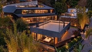 Una casa moderna de varios pisos con un amplio patio descubierto, rodeado de vegetación exuberante.