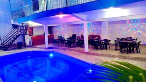 Area piscina con zona relax coperta e una scala che conduce a un livello superiore.