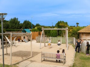 Ein Spielplatz mit Schaukeln, einer Rutsche und einer hölzernen Bank.
