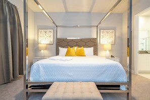 A modern hotel room with a large bed, two bedside lamps, and a decorative headboard. - Reunion Resort Stay • Spacious 3BR • Ground Floor (Kissimmee)