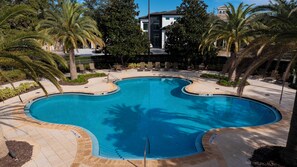 A swimming pool with a unique shape surrounded by palm trees and lounge chairs. - Reunion Resort Stay • Spacious 3BR • Ground Floor (Kissimmee)