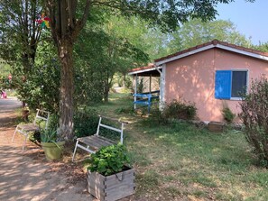 Un chalet rustique avec un banc en bois et un petit coin jardin.