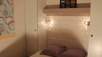 Une chambre avec un lit superposé, une armoire et une étagère murale décorée de tableaux.