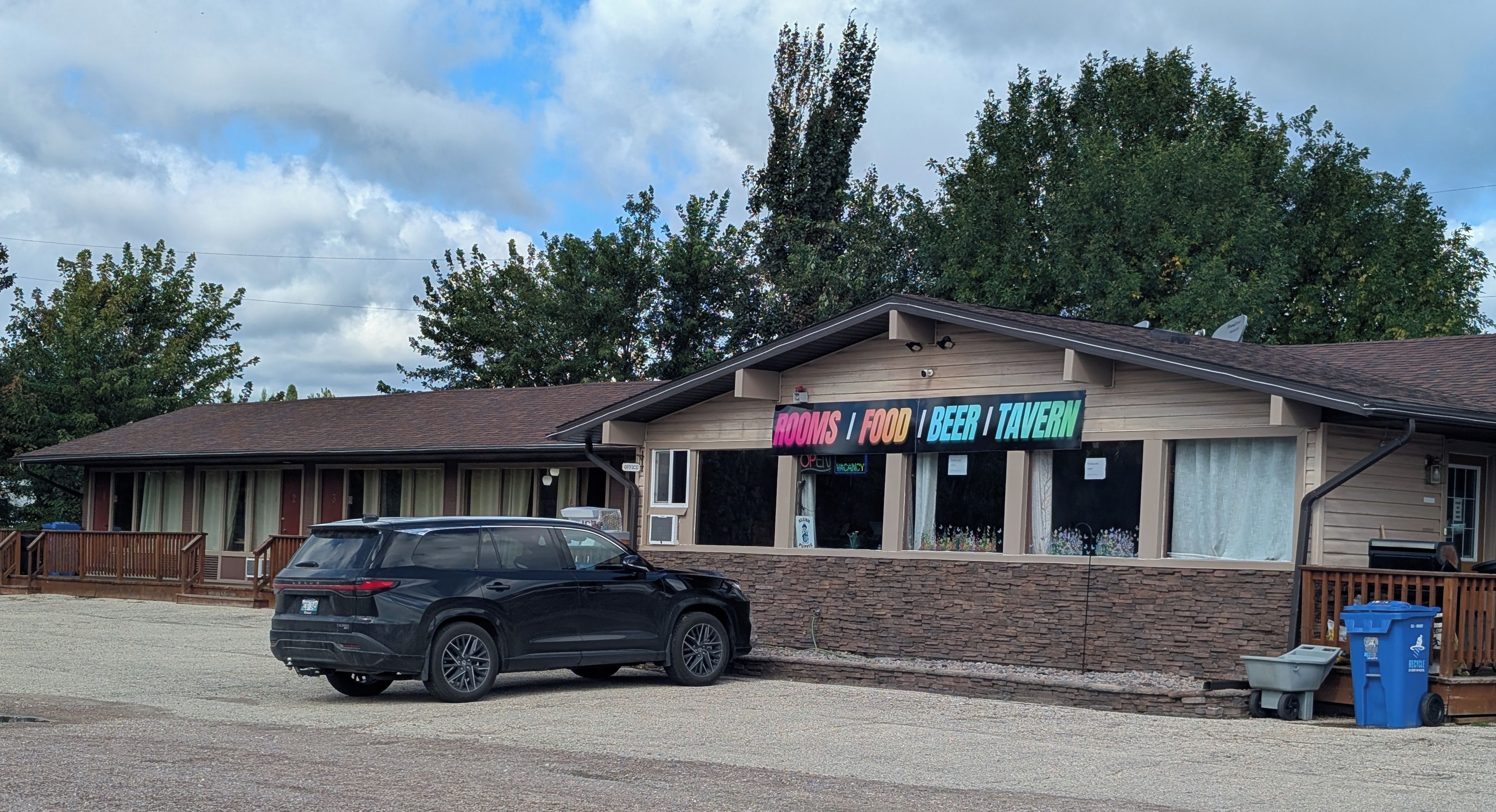 A building with a sign advertising rooms, food, beer, and a tavern.