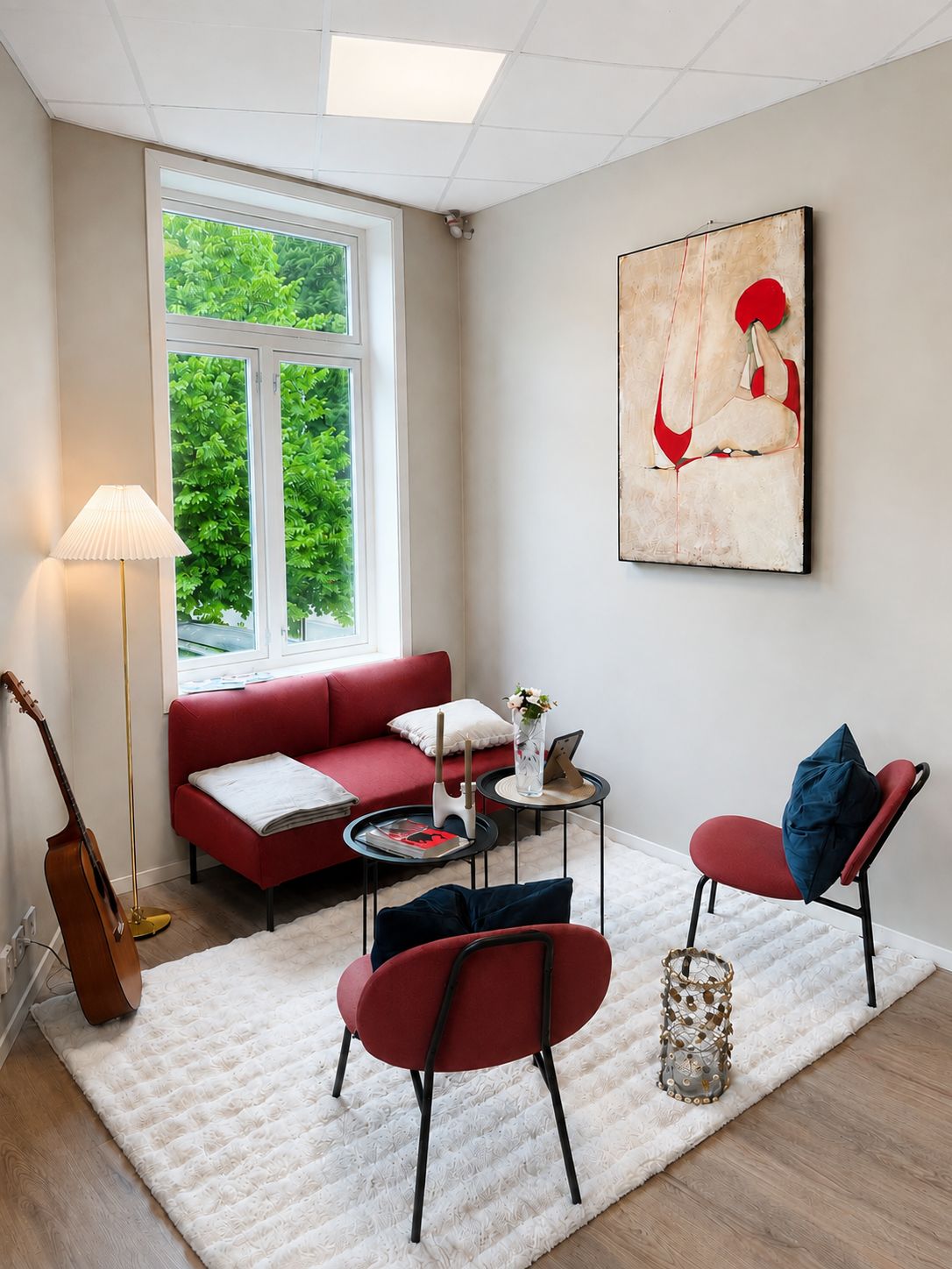 A living room with a red sofa, a white rug, a coffee table, and a painting on the wall.