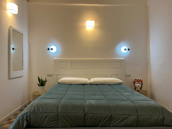 Ein Schlafzimmer mit einem Bett, zwei Wandleuchten, einem Nachttisch mit Pflanze und einer Dekoration.