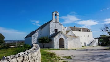 A white church with a bell tower and a stone wall in the foreground.