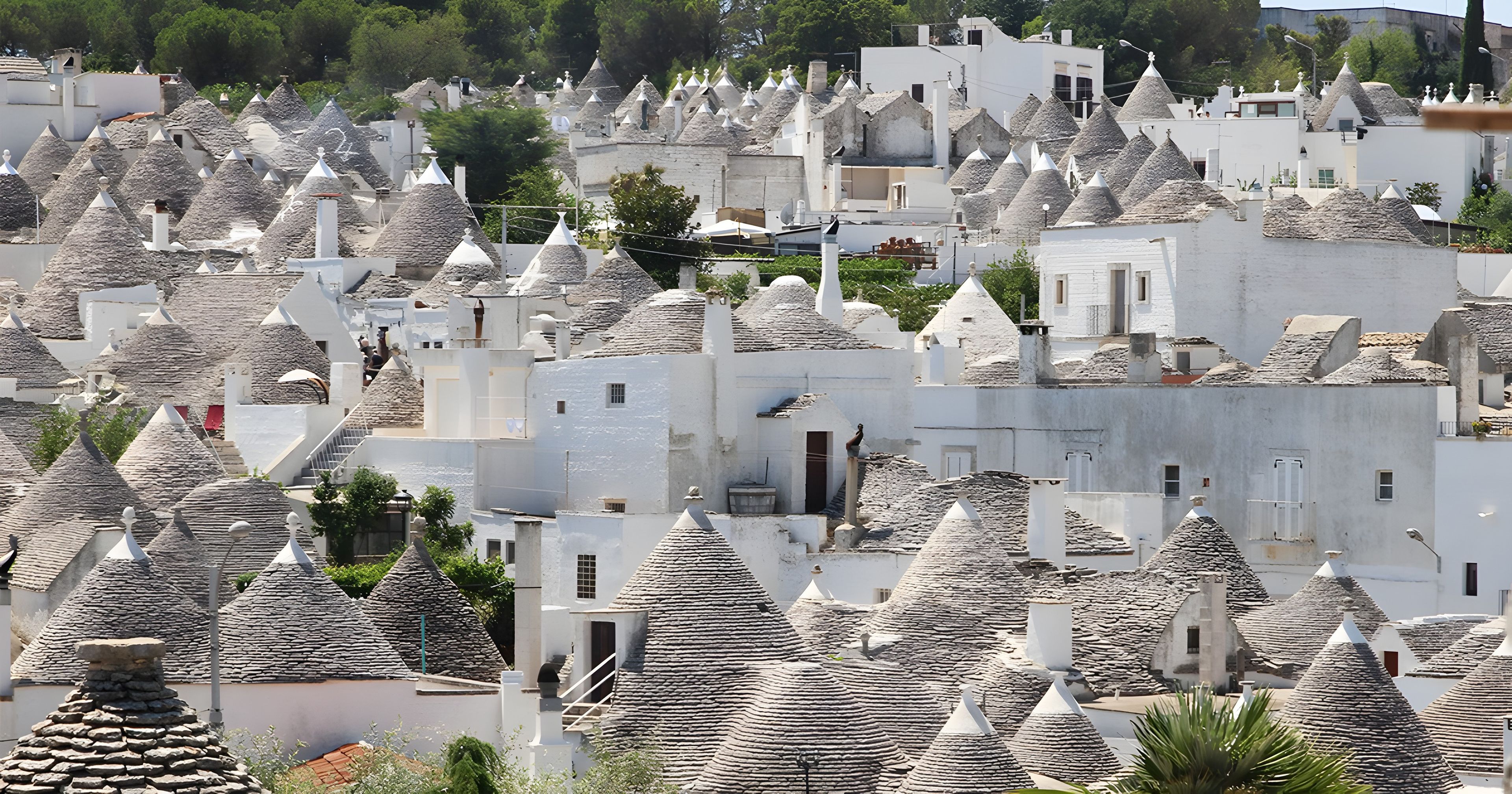 A densely packed village with numerous white buildings featuring conical roofs.