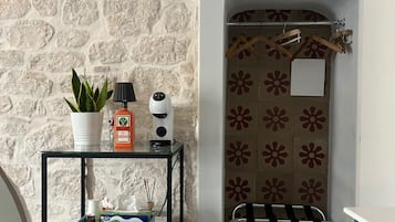 A compact bathroom with a stone wall, a small table with toiletries, a towel rack, and a radiator.