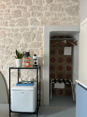 Een compacte badkamer met een stenen muur, een klein tafeltje met toiletartikelen, een handdoekrek en een radiator.