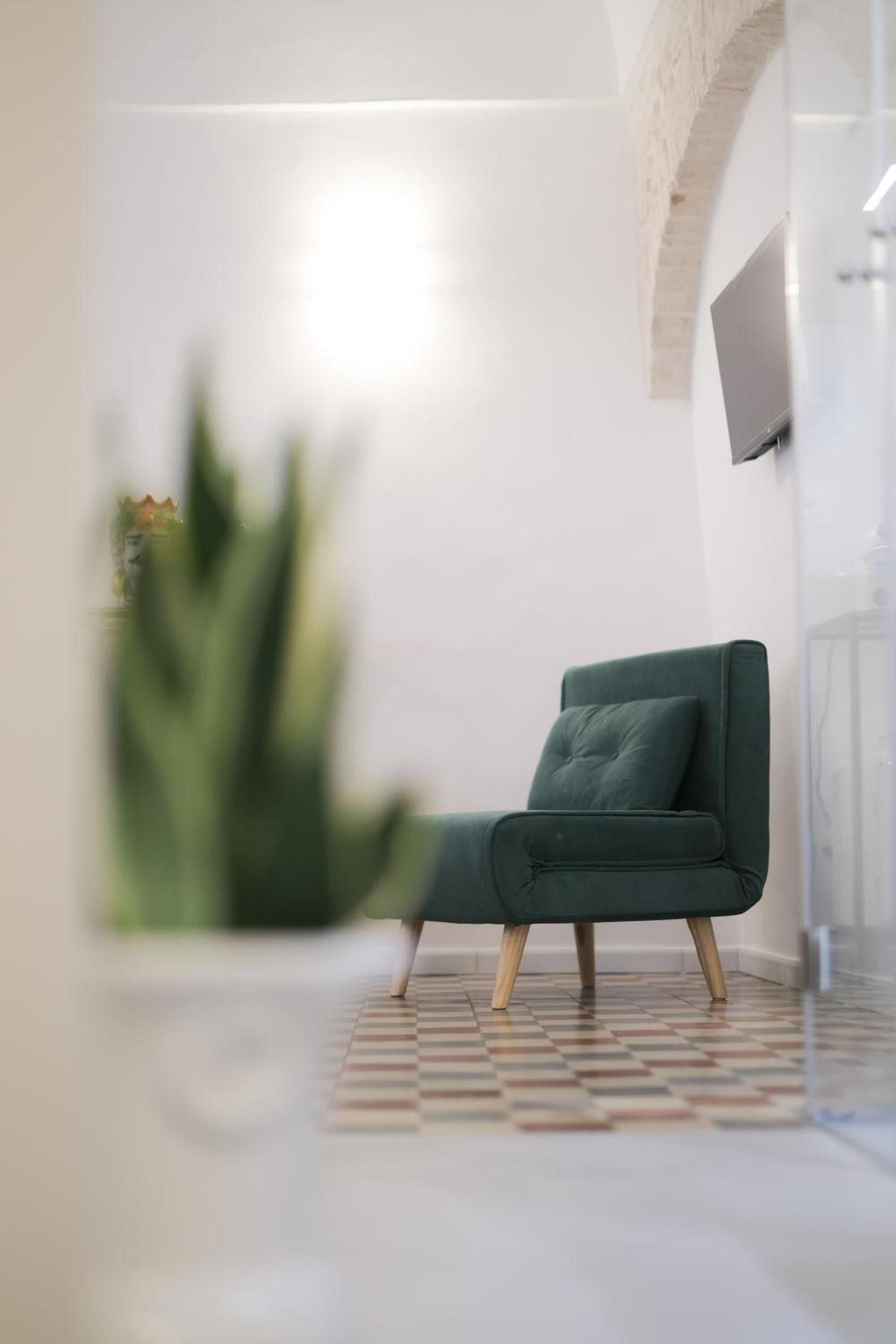 A modern room with a green chair, a patterned floor, and a TV mounted on the wall.