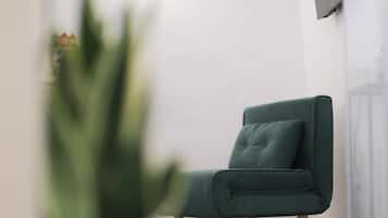 A modern room with a green chair, a patterned floor, and a TV mounted on the wall.