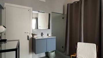 A hotel room with a bathroom, a chair, a sink, and a mirror.