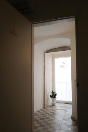 An interior hallway with a checkered floor, a white wall, and a potted plant. - Room 'Pepenero Apulian Rooms - Loggetta' with Wi-Fi and Air Conditioning (Noci)