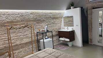 A bathroom with a stone wall, a wooden drying rack, a white sink, and a mirror.