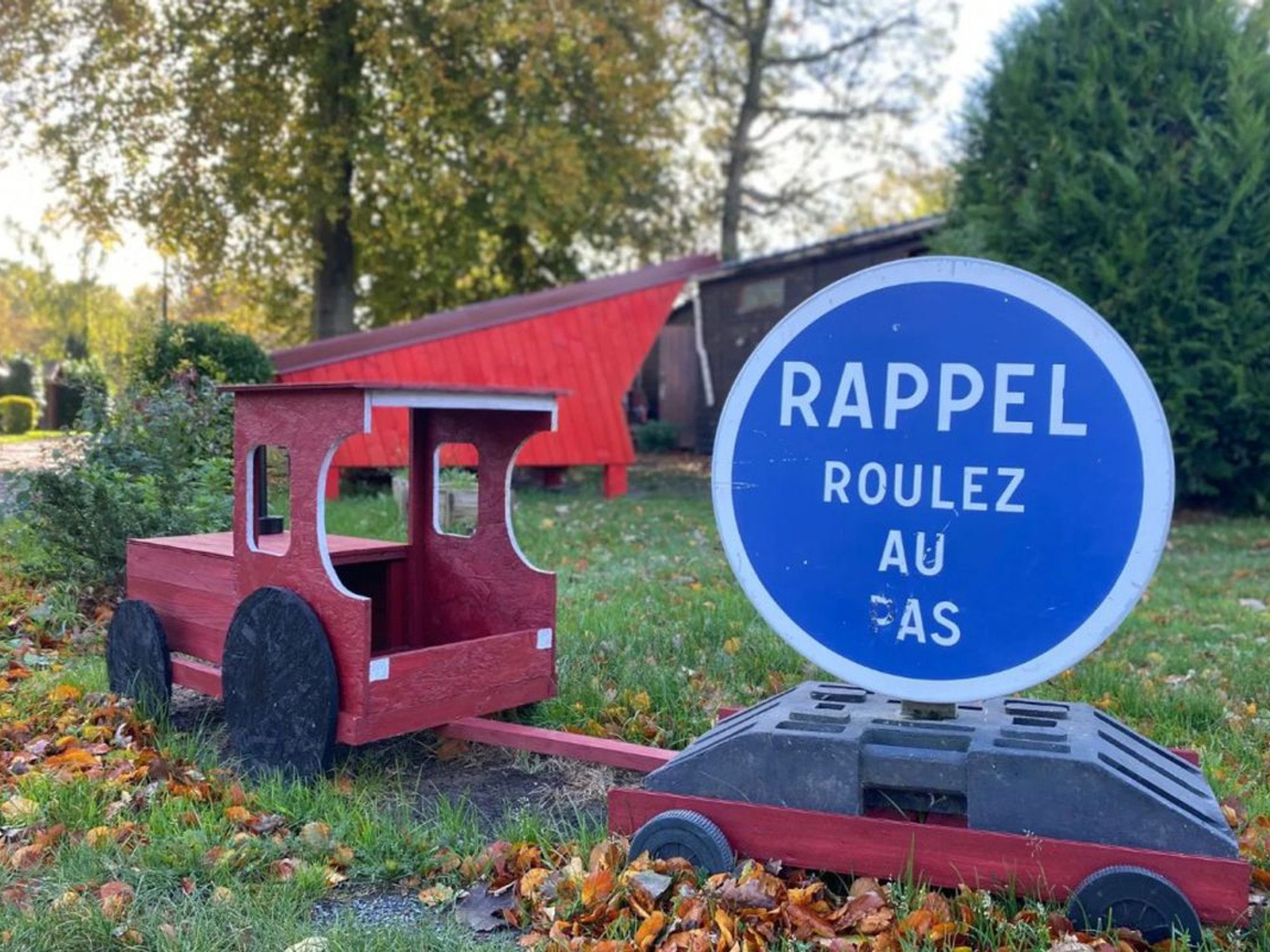 Un petit train jouet rouge et une pancarte avec l’inscription « Rappel Roulette AU FAS ».