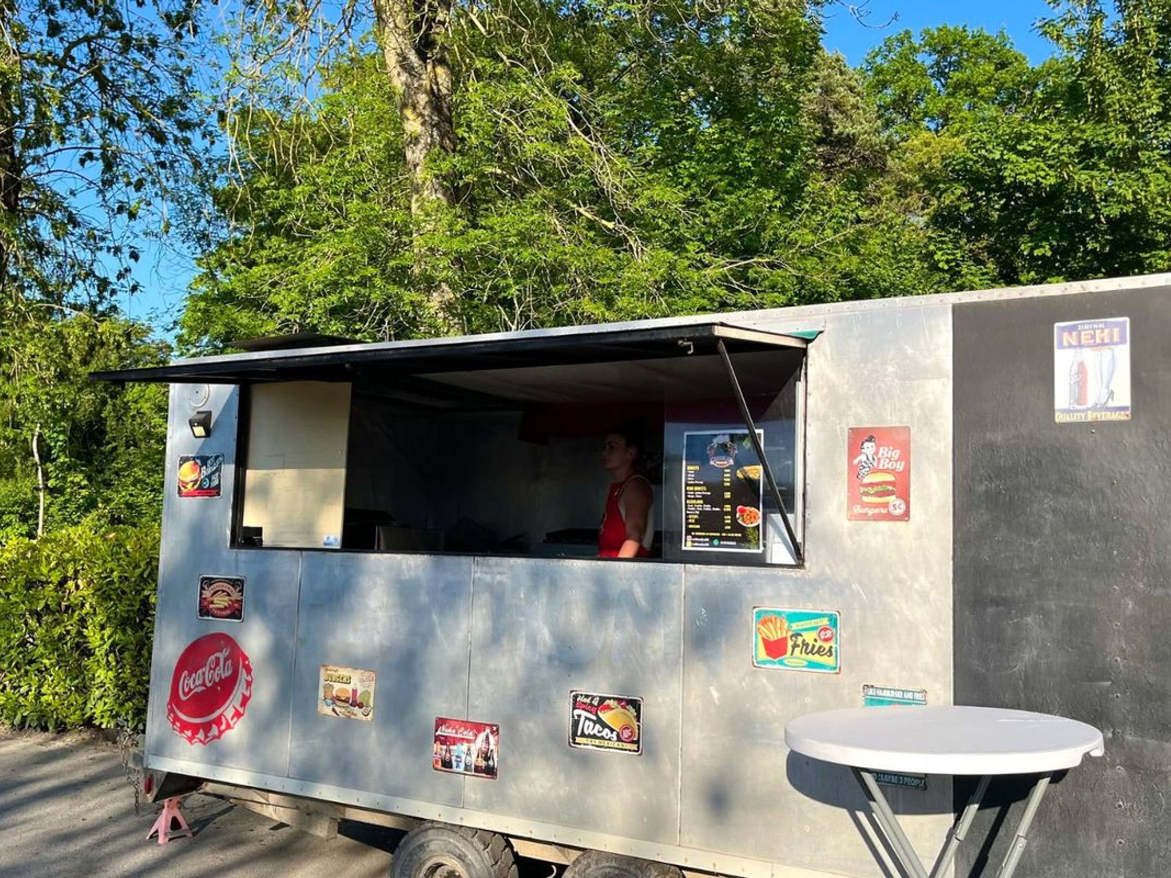 Un camion-restaurant arborant le logo Coca-Cola, avec un panneau affichant le menu et une enseigne représentant le hamburger Big Boy.