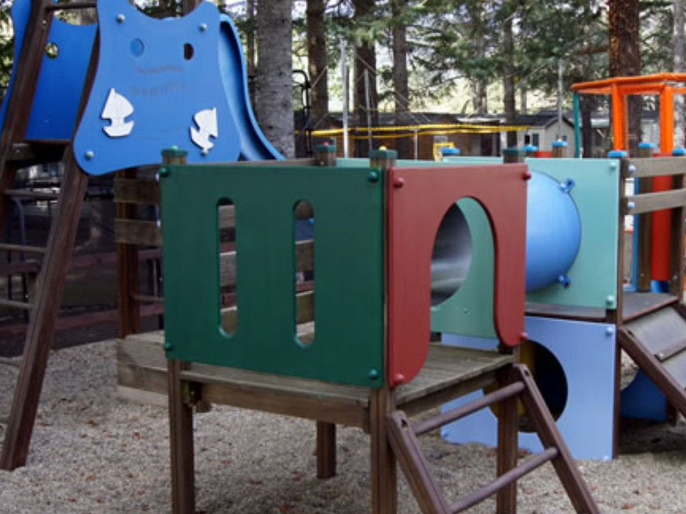 A playground with various play structures including a blue slide and climbing frames.