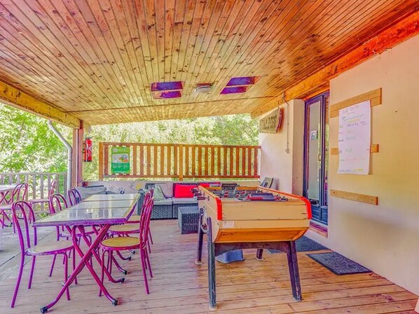 An outdoor area with a foosball table, seating, and a bulletin board.