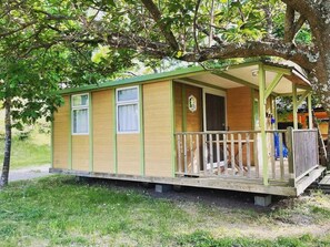 A small, single-story wooden cabin with a porch, windows, and a door.