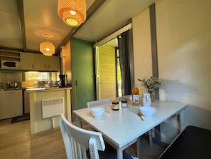 A compact kitchen with a dining area, featuring a table with bowls, a pitcher, and jars.