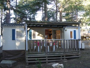 A small cabin with a porch, a door, and a window. - Mobile home with AC, pets OK - 6 guests (Sournia)