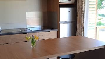 A modern kitchen with a wooden countertop, stainless steel appliances, a microwave, and a refrigerator.