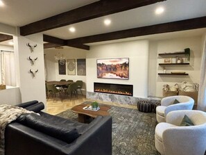 A modern living room with a fireplace, leather sofas, and a dining area in the background.
