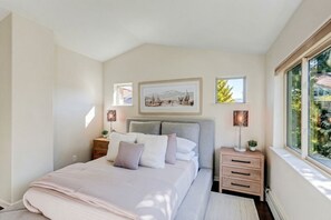 Un dormitorio con cama, mesitas de noche, una ventana y decoración en la pared.