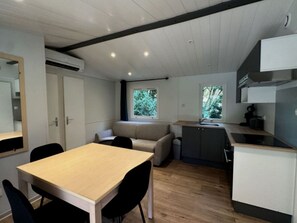 Una cocina compacta con una mesa, sillas, una banca integrada y un ventanal.