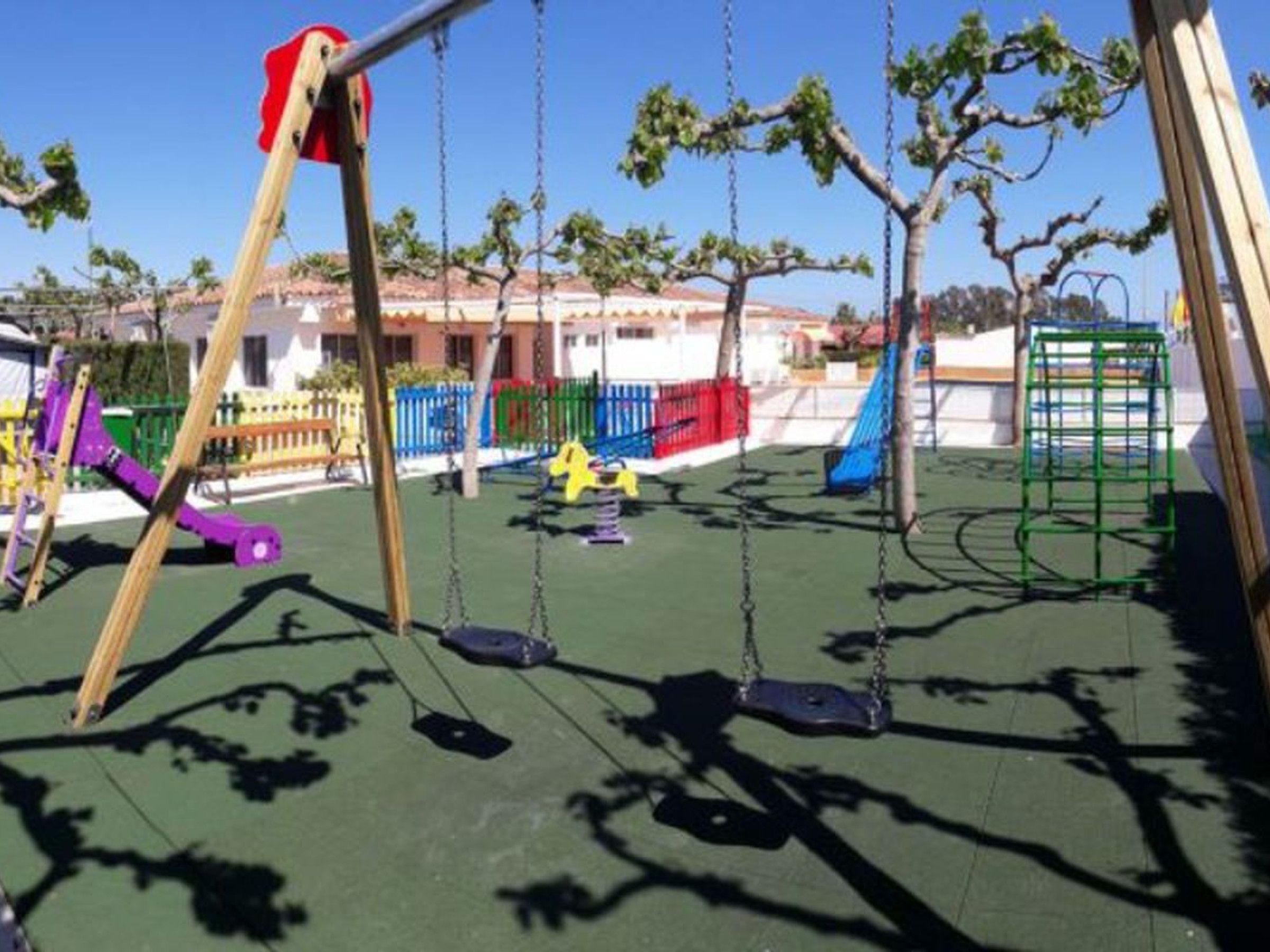 Un parque infantil con columpios y un tobogán.