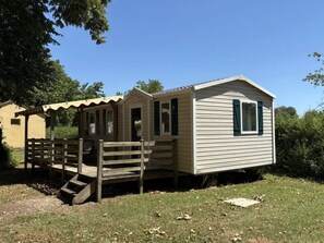 A single-story mobile home with a porch and a small attached structure, possibly a garage or storage area. - Spacious mobile home with terrace - 8 guests (Athée)