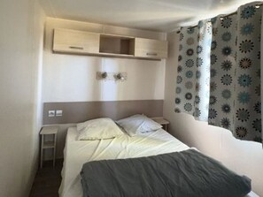 Ein Einzelbett mit Kopfteil, Nachttisch und kleines Regal darüber.