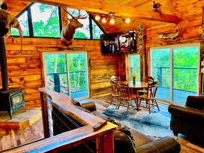 Een rustiek houten interieur met een eettafel, stoelen, een bar en een televisie aan de muur.