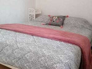 Ein Bett mit einem gemusterten Überwurf und einer rosa Decke.