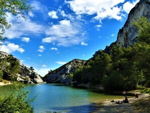 Un paysage naturel caractérisé par un ciel bleu dégagé, une étendue d’eau calme et des falaises rocheuses.