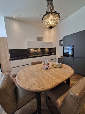 Eine moderne Küche mit einem runden Holztisch, dunklen Schränken und einem dekorativen Kronleuchter.