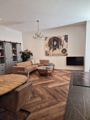 Ein modernes Wohnzimmer mit einer Couch, einem Couchtisch und einem Fernseher.