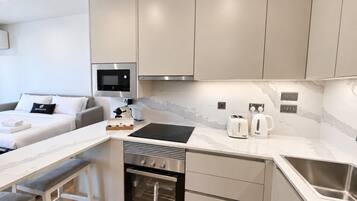 A compact kitchenette with a microwave, toaster, and kettle, a small oven, and a sink.